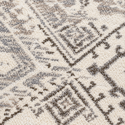 Afterimage area rug: close-up of a ttextured area rug with a geometric tribal pattern in cream, taupe, and dark brown.