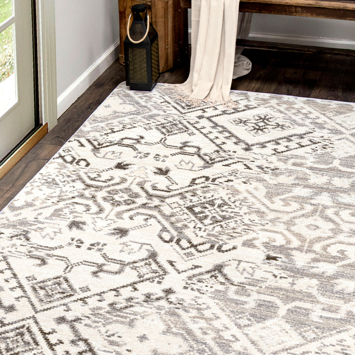 Afterimage area rug: patterned area rug on a wooden floor with a window and curtain in the background.