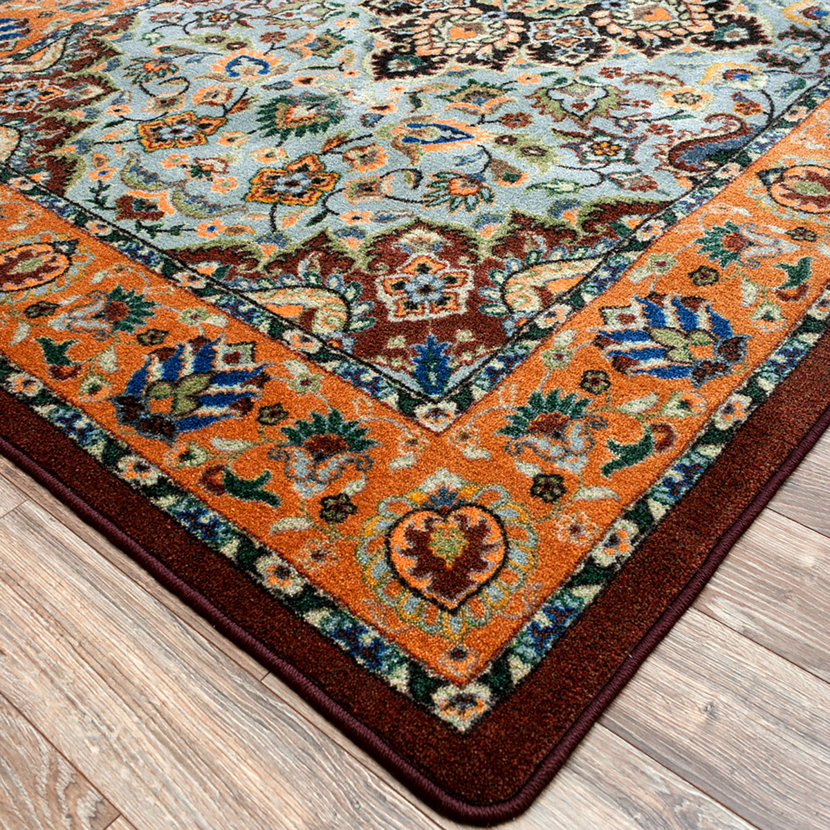 Close up of the corner of the Bright Side orange and blue area rug with persian inspired graphics in modern color palette nylon fibers and pet friendly and kid friendly low voc anti allergen.