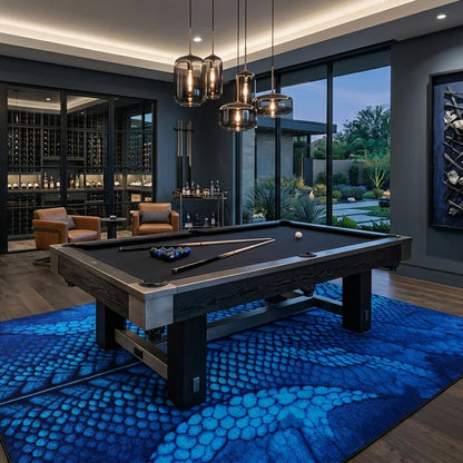 A dark wood pool table with a black felt surface is shown in a modern luxury room with a large blue patterned rug, wine cellar in the background, and outdoor garden views.