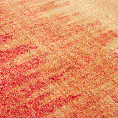Color Rush area rug: a close-up of a ttextured carpet or rug with a mottled pattern of red and warm beige tones.