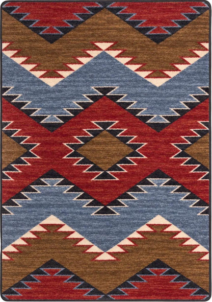 Crossplay area rug: a rectangular area rug with a Southwestern geometric pattern featuring red, brown, slate blue, cream, and black zigzag and diamond motifs.