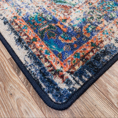 Close up of the Daydream area rug showing serged corner and heavy distressing bold navy color mixed with orange and yellow energetic yet classic.