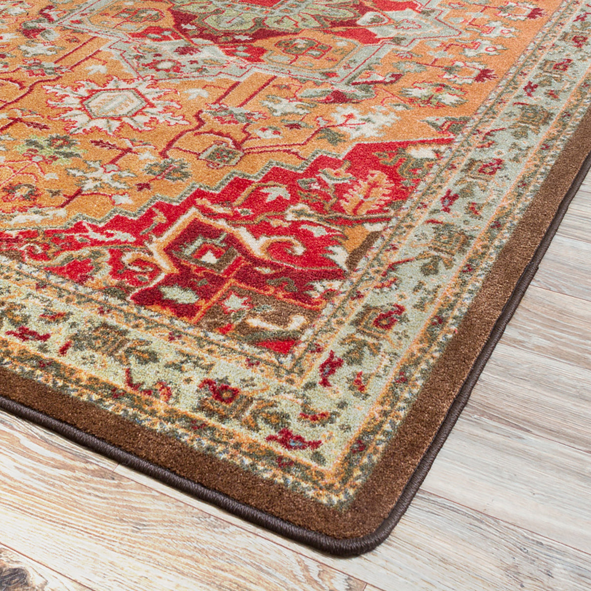 Firelight area rug: a close-up of a traditional area rug with a warm orange, red, and brown pattern, shown on a light wood floor.