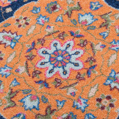 Full House area rug: close-up of a ttextured area rug featuring a vibrant orange center with a detailed floral medallion in blue, pink, green, and cream, surrounded by a dark navy blue border.