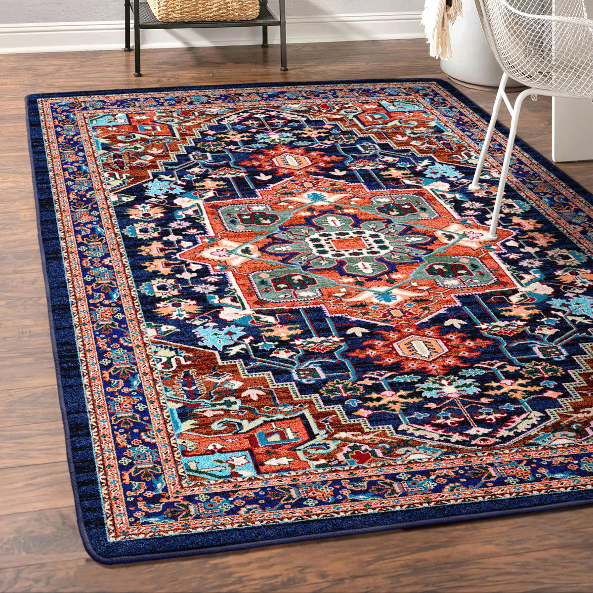 Good Company area rug: decorative rug with intricate patterns on a wooden floor, with a chair and plant in the background.