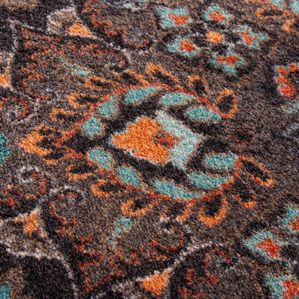 House Special area rug: close-up of a ttextured area rug with a traditional medallion pattern in dark brown, orange, and turquoise blue.