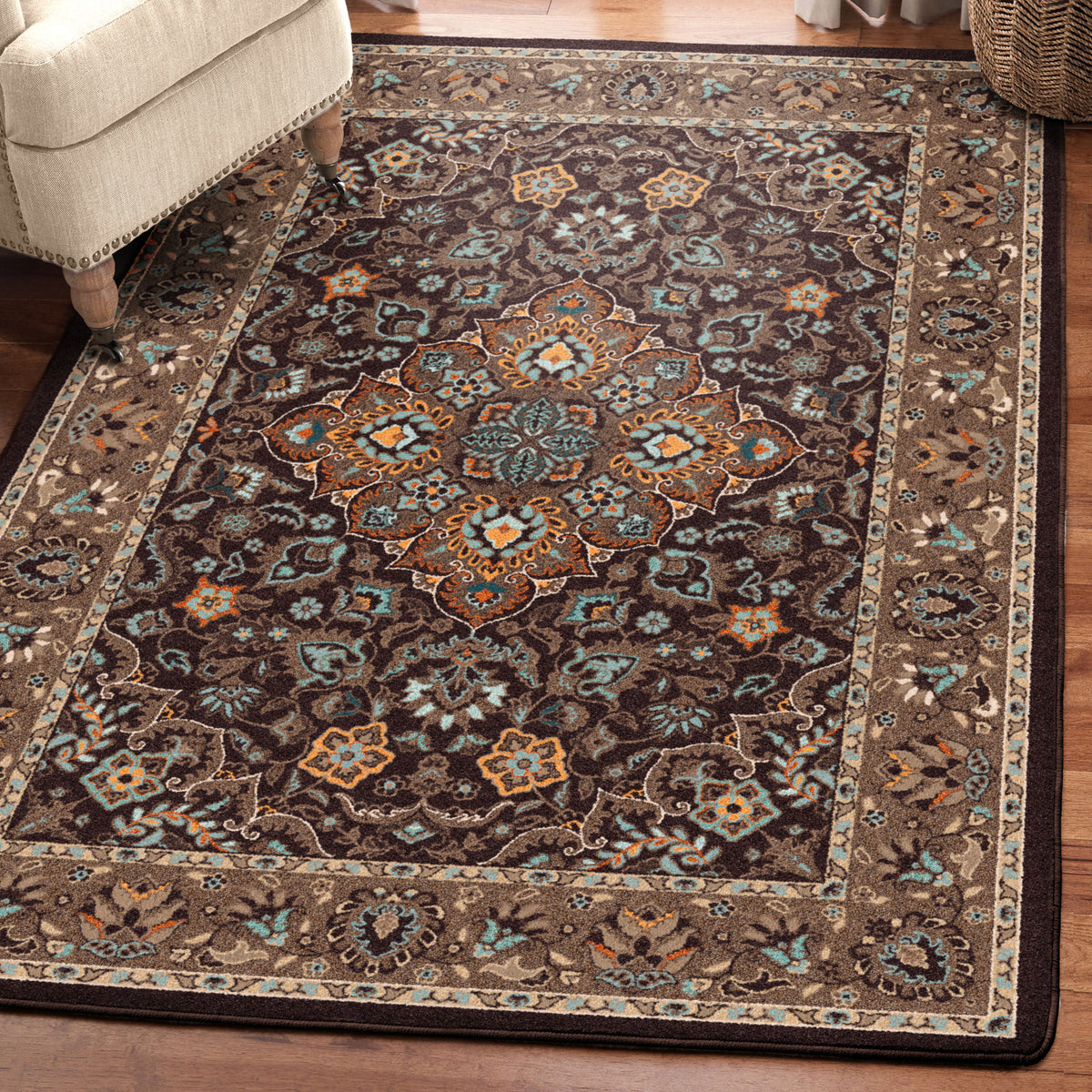 House Special area rug: a rectangular area rug with an intricate traditional floral pattern in dark brown, beige, and muted blue, shown on a hardwood floor next to a cream-colored armchair.