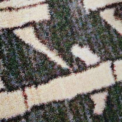 Close-up of a textured area rug with a geometric pattern in dark green, cream, and brown.