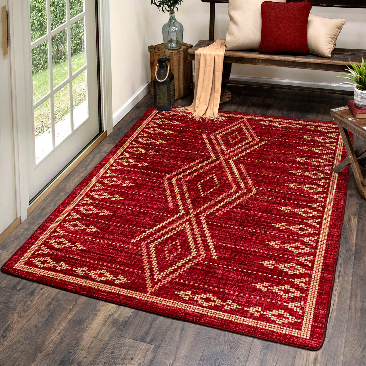 Red patterned rug on a wooden floor with a bench and decor items in the background.