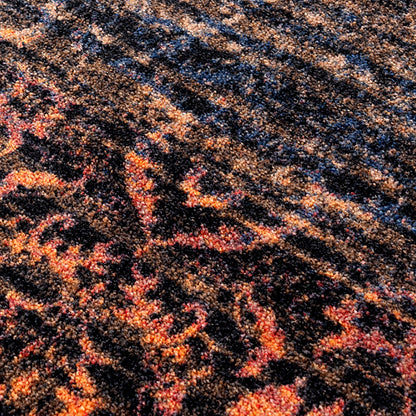 Last Call area rug: a close-up of a ttextured rug or carpet with an abstract, ornate pattern in black, orange, red, and blue.