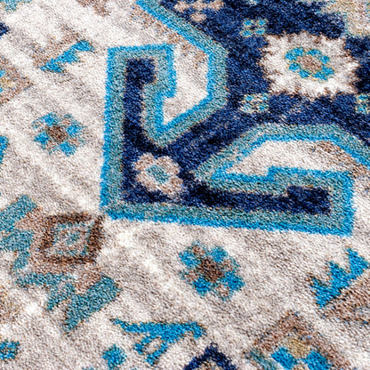 Close-up of a textured area rug with a geometric pattern in navy blue, light blue, beige, and brown.