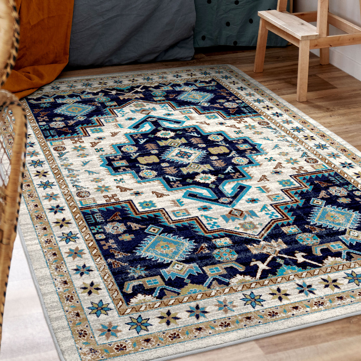 A rectangular area rug with a traditional geometric medallion pattern in navy blue, cream, and turquoise, shown on a light wood floor in a room setting.