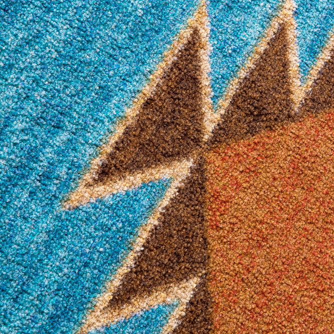 Close-up of a ttextured rug featuring a geometric pattern with a bright blue background, brown and beige triangular shapes, and a rust-orange block.